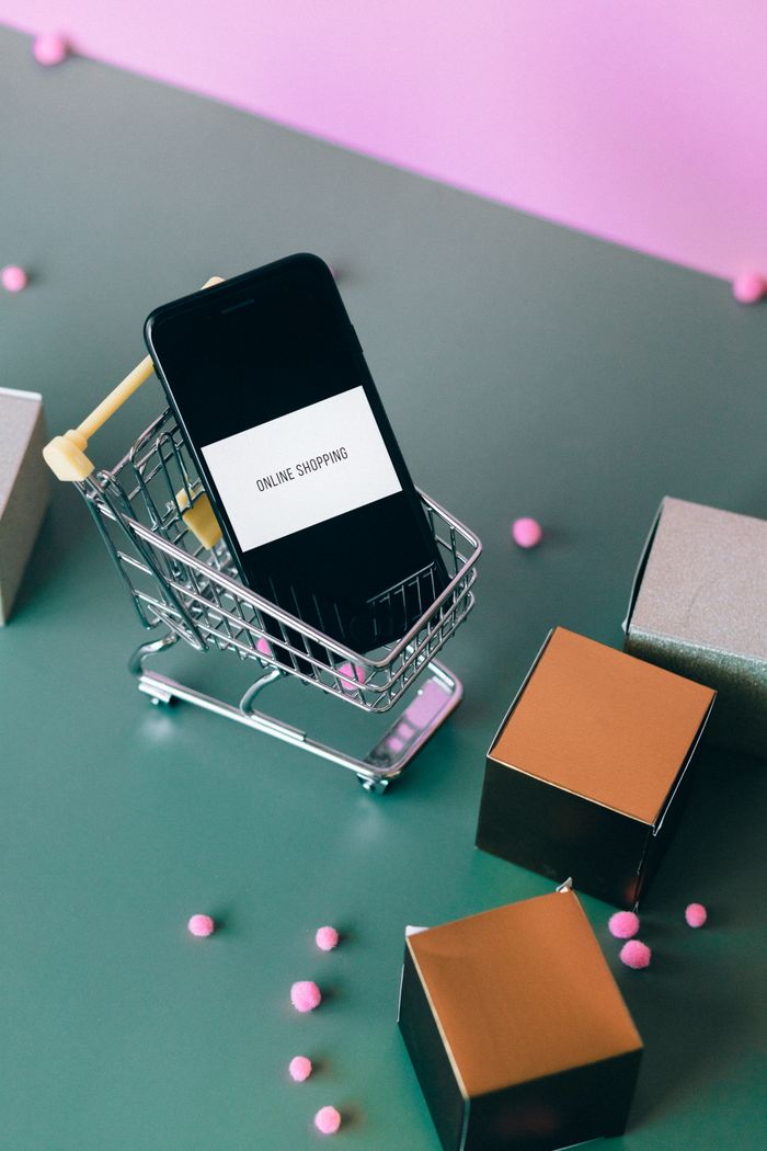 services-02 Conceptual image of online shopping with a smartphone in a miniature cart.